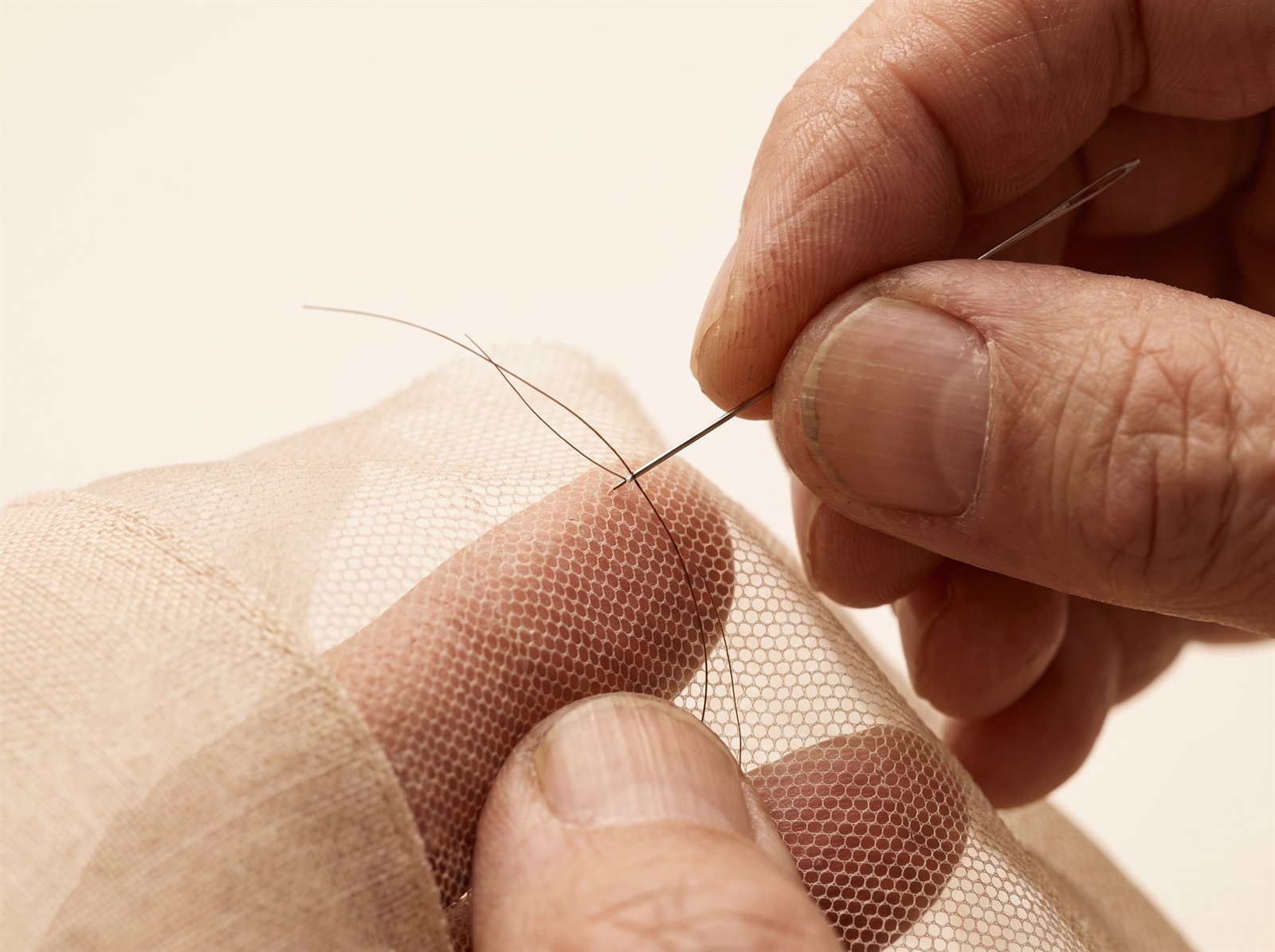 A ventilating needle tying a single hair into translucent French lace